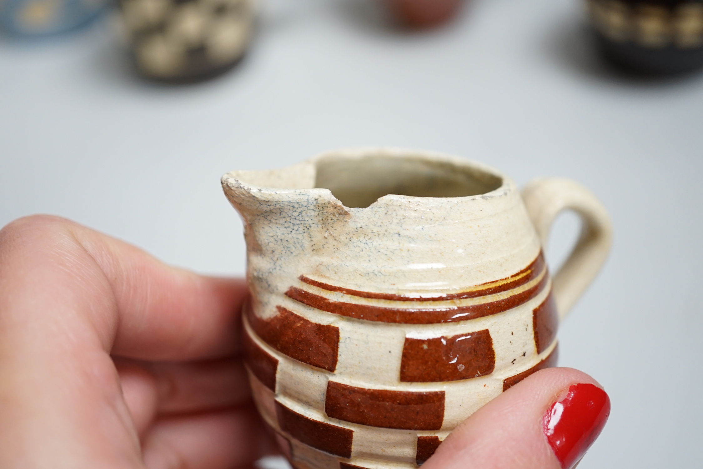 Eight 19th century slip-decorated creamware chequer-pattern jugs and mugs, tallest 10cm